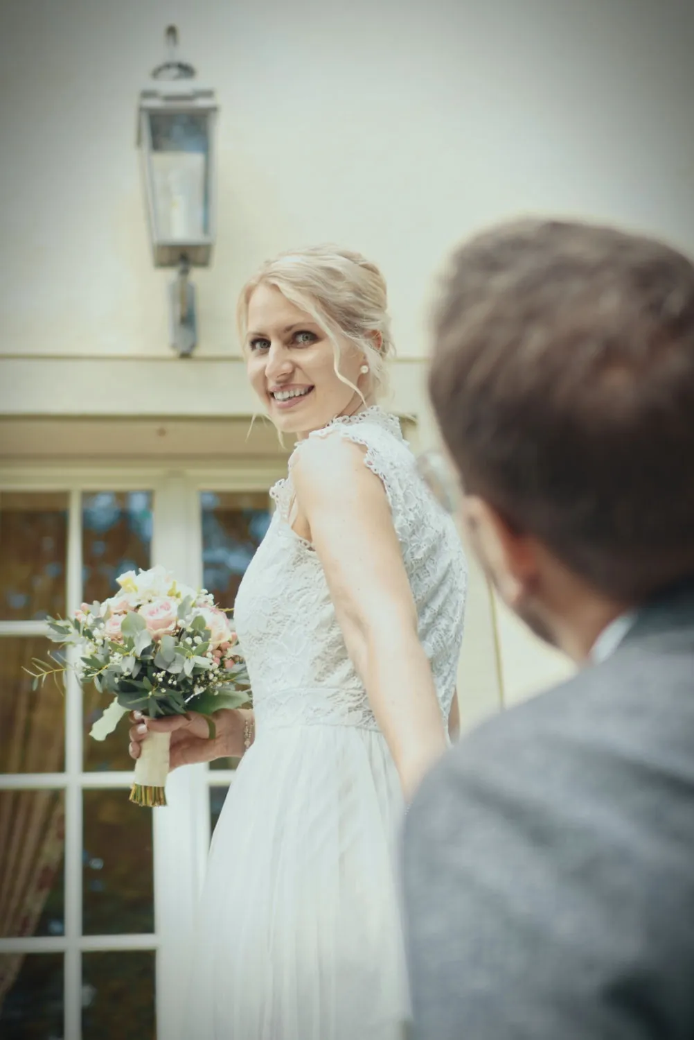 Braut schaut nach hinten zum Brätigam. Hochzeitspaar vor dem Schlosshotel Friedrichsruhe